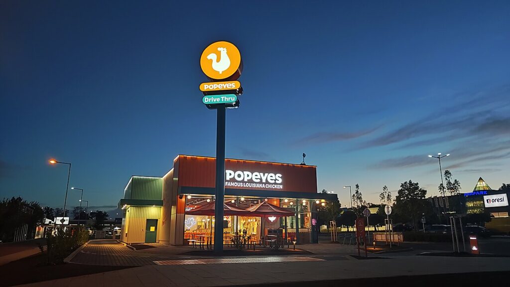 Wolnostojąca restauracja Popeyes z drive-thru wieczorem